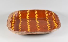 A SLIPWARE BAKING DISH decorated with cream slip winding trails, believed 19th Century, 32cms long