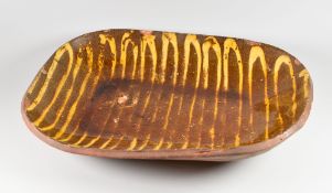 A SLIPWARE BAKING DISH of irregular form with cream slip continuous trail, believed 19th Century,