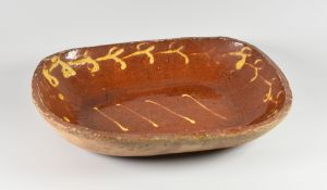 A SLIPWARE BAKING DISH with four-line cream slip decoration to the interior and trail to the border,