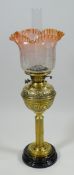 AN ANTIQUE OIL LAMP with brass reservoir & column to a black ceramic circular base, the brasswork