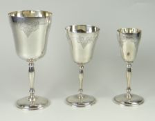 GRADUATED SET OF THREE SILVER GOBLETS decorated with berry & leaf detail, raised on circular