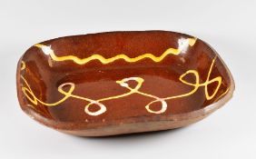 A SLIPWARE BAKING DISH decorated with three cream slip trails, believed 19th Century, 34cms long