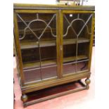 A VINTAGE OAK TWO DOOR BOOKCASE with interior adjustable shelves, on bulbous front supports, 129.5