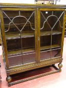 A VINTAGE OAK TWO DOOR BOOKCASE with interior adjustable shelves, on bulbous front supports, 129.5