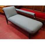 AN EDWARDIAN CHAISE LONGUE with spindleback rail and carved front detail on turned supports with