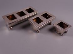 A SET OF THREE OBLONG SILVER STAMP HOLDERS, all with drum shaped bases on ball feet, being a single,