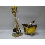 A SET OF VICTORIAN BRASS FIRE IRONS on a stand with a vintage brass coal scuttle on four claw feet
