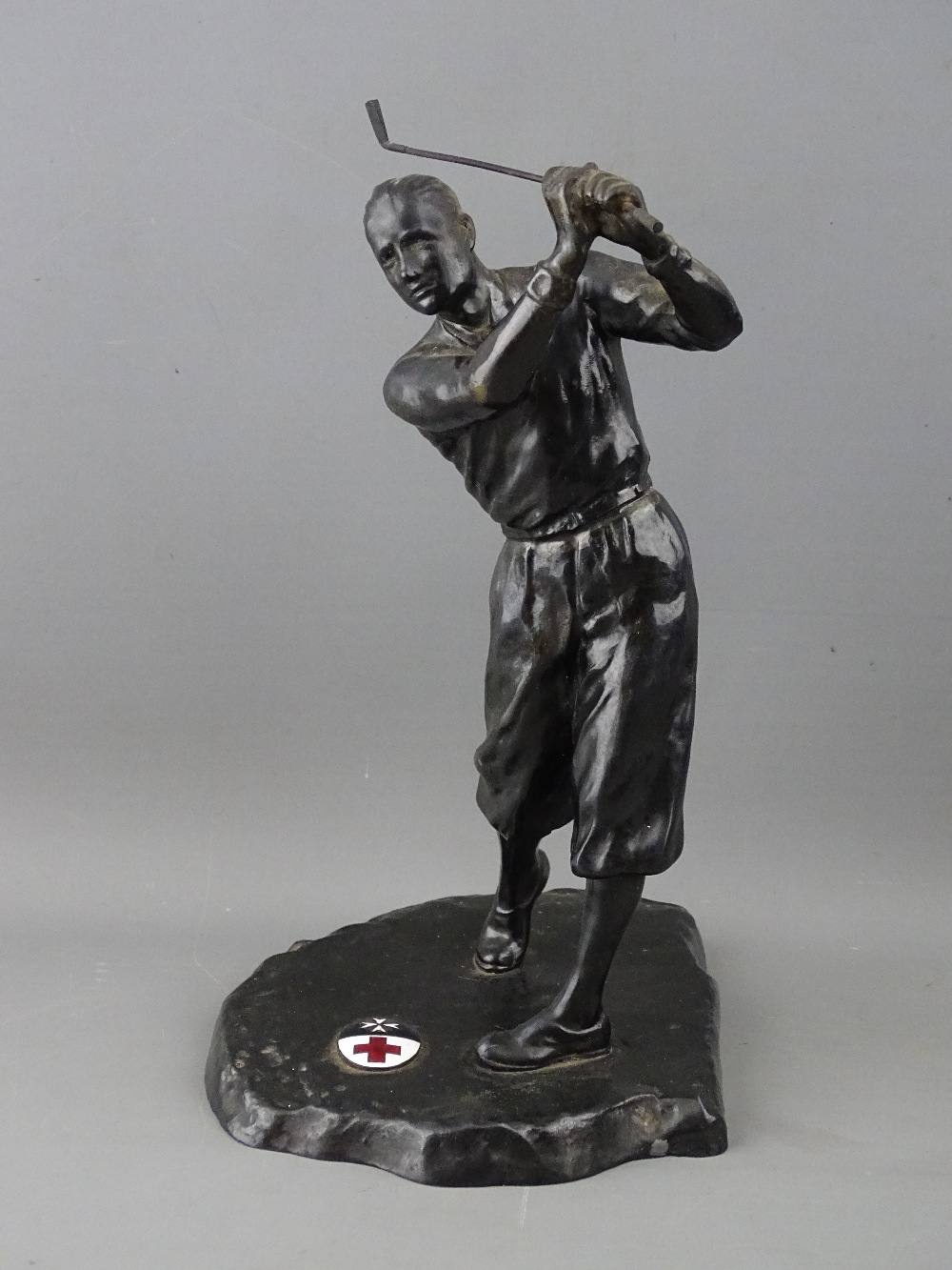 A VINTAGE CAST METAL FIGURE OF A GOLFER, the base set with an oval enamel plaque showing the emblems