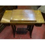 A SINGER TREADLE SEWING MACHINE in an oak fold-out work table, 77.5 cms high, 87 cms wide, 41.5