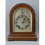 A DOME TOPPED MAHOGANY EDWARDIAN MANTEL CLOCK, the silvered dial set with Roman numerals and slow-