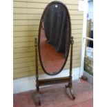 A REGENCY STYLE MAHOGANY OVAL DRESSING MIRROR with reeded and gilt highlighted decoration and cone