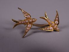 AN UNMARKED GOLD BAR BROOCH with twin flying swallows encrusted with seed pearls, 3.4 grms