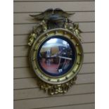 A REGENCY STYLE GILT CONVEX WALL MIRROR with eagle cresting and ball detail, 81 cms long overall, 53