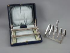 A CASED PAIR OF SILVER KNIFE RESTS and a four section silver toast rack, Birmingham 1900 and 1937