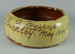 A BUCKLEY POTTERY SLOP BOWL in yellow slip inscribed 'A Present from Buckley May 1894' and with