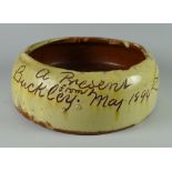 A BUCKLEY POTTERY SLOP BOWL in yellow slip inscribed 'A Present from Buckley May 1894' and with