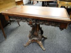 An antique mahogany fold-over card-table with baize lined interior having an elaborately carved