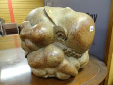 An interesting carved sculpture of a Buddha-type figure in a distressed position with his head