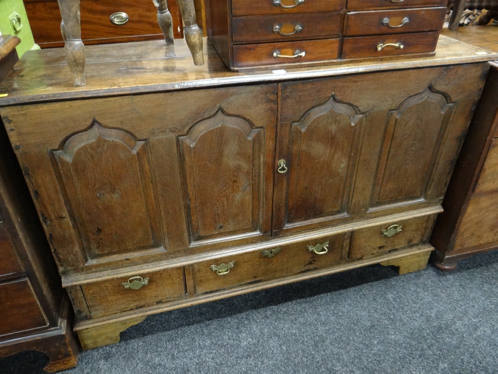 An antique oak four panel blanket chest with three base drawers on bracket feet (converted to drinks