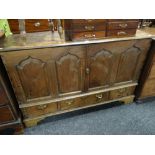 An antique oak four panel blanket chest with three base drawers on bracket feet (converted to drinks
