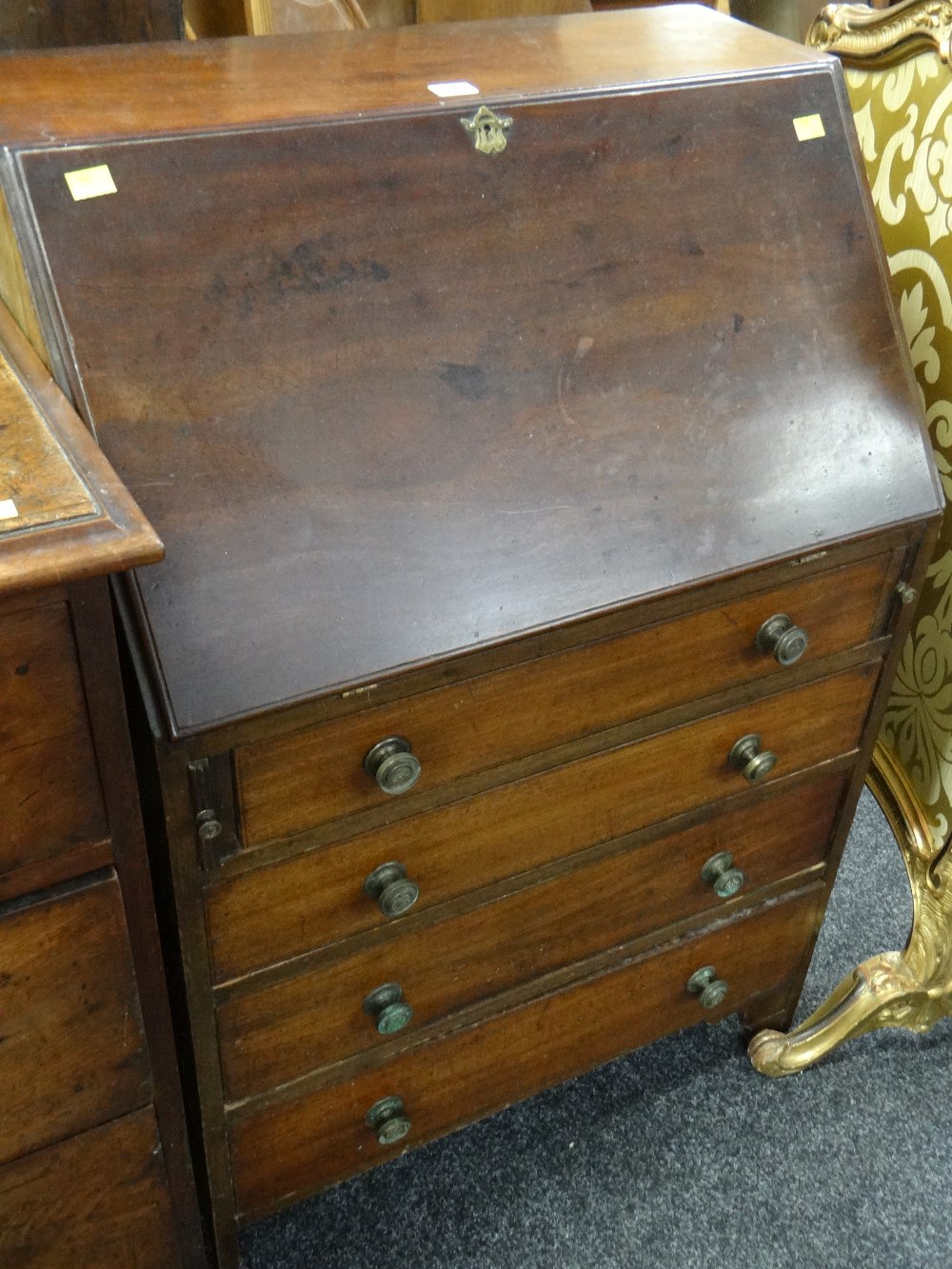 A small antique mahogany bureau composed of four graduated drawers, the sloped front revealing