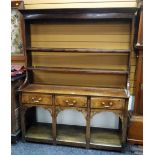 An attractive small antique mixed wood Welsh dresser having a solid platform base, three drawers, an