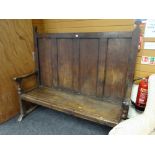 An antique oak settle having a four-panel back & with single plank seat on turned & block