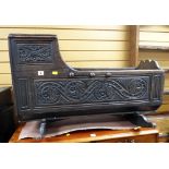 An antique carved oak rocking crib, primitively carved with foliate panels Condition Report: