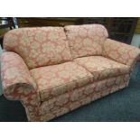 A pair of floral upholstered pink two seater sofas & a similarly upholstered wing back armchair