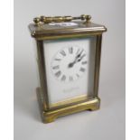 A brass encased carriage clock with white enamel dial bearing Roman numerals & inscribed E J