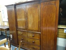 A Victorian mahogany triple breakfront wardrobe composed of flanking hanging space, press cupboard
