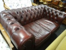 A two-seater cherry coloured leather Chesterfield settee Condition Report: please request via email.