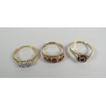 Three gold rings including three-stone diamond ring, garnet ring (one stone missing) Condition