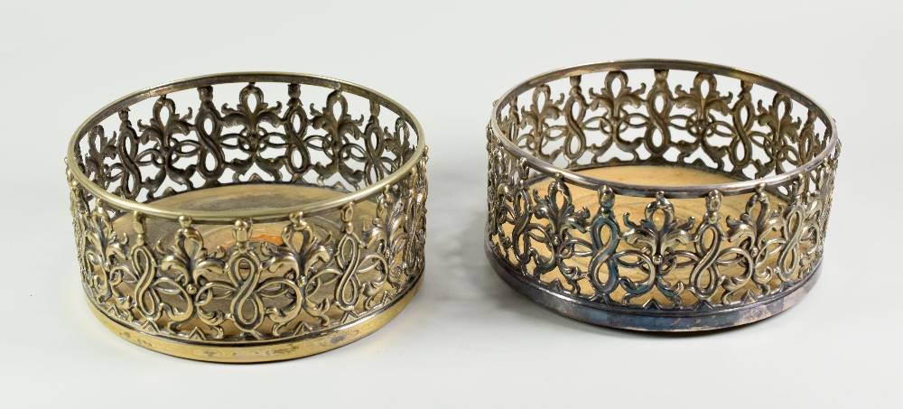 PAIR OF PIERCED SILVER PLATED BOTTLE COASTERS, having turned wooden bases. 14cm diameter. (2)