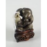 BELIEVED CHINESE BLACK & WHITE JADE CARVED MONKEY GROUP raised on carved hardwood base, 9.5cms