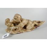 CARVED SOAPSTONE STUDY OF A MAN GRIPPING ONTO A SMALL MYTHICAL-TYPE BEAST on naturalistic leaf base,