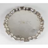 GEORGE V SILVER PIE CRUST EDGE SALVER, raised on three scroll feet and engraved "Llewelyn & Edith