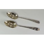 TWO SIMILAR EARLY 19TH CENTURY SILVER BERRY SPOONS, with embossed and engraved decoration and