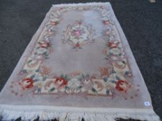 A mushroom coloured Chinese washed woollen rug with floral pattern & tasselled ends