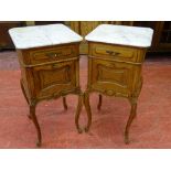 A PAIR OF FRENCH OAK BEDSIDE CABINETS with white marble tops and cupboard interiors having carved