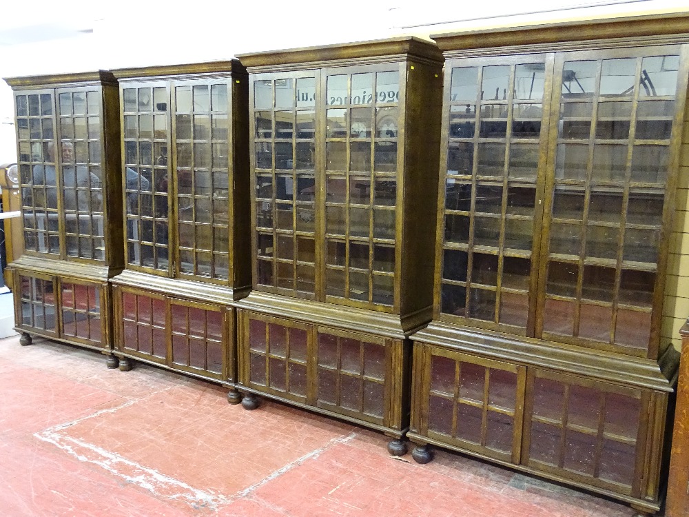 A GOOD SET OF FOUR 20th CENTURY OAK DOUBLE BOOKCASES having multi-panelled twin upper and lower