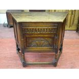 A REPRODUCTION OAK SINGLE DOOR SIDE CABINET with carved front detail on turned and block supports,