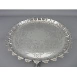 A CIRCULAR SILVER TRAY with chased decoration and raised pierced pattern border, on four scrolled