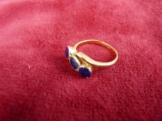 A LADY'S EIGHTEEN CARAT GOLD DRESS RING having three possibly lapis round cut stones in a
