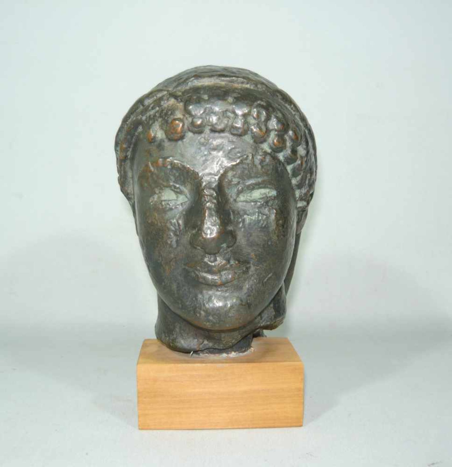 Museumsreplik eines antiken Kopfes. Wohl Bronze, auf Holzsockel montiert. H. inkl. Sockel ca. 19
