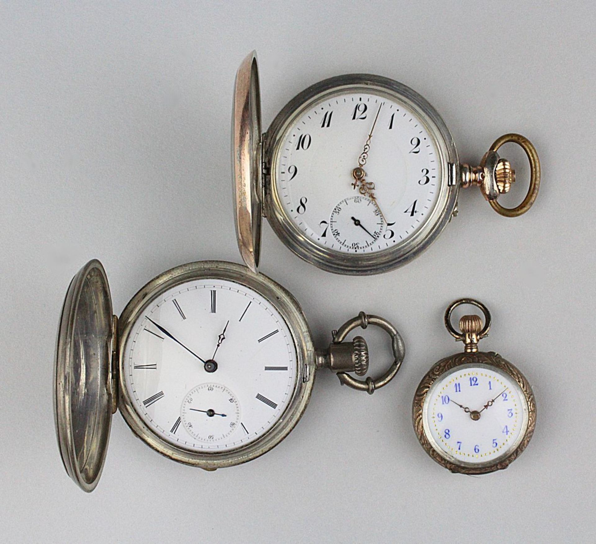 3 silberne Taschenuhren: eine Schlüsseltaschenuhr mit Sprungdeckel, Glas fehlt, Zylinderwerk,