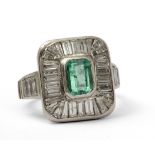 An emerald cluster ring. Platinum, 1,20 ct. central emerald cut emerald with baguette and taper cut