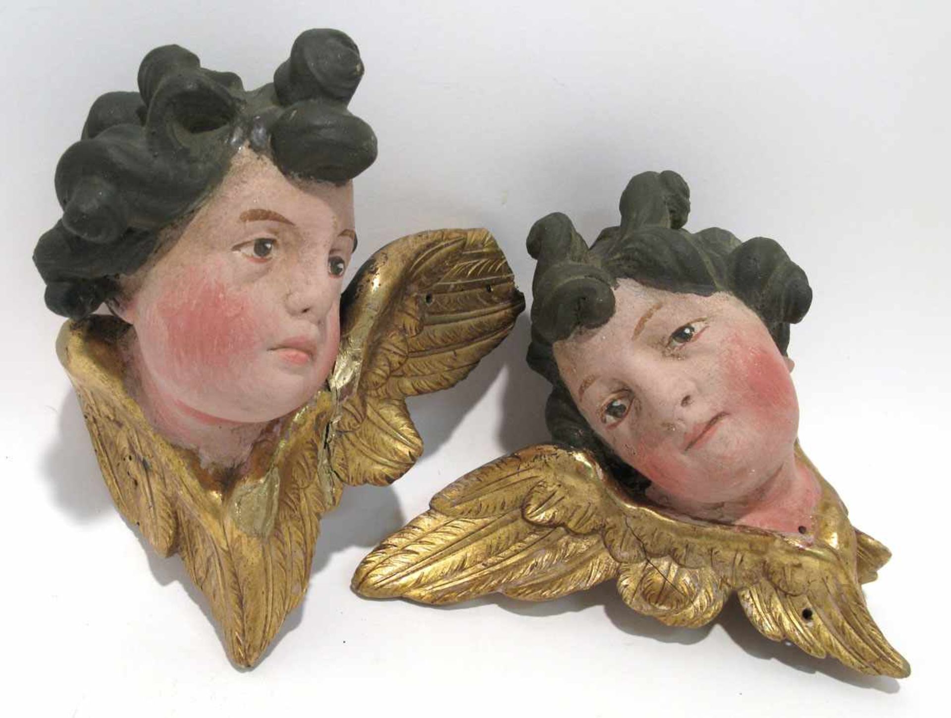Zwei geflügelte Puttenköpfe Barockstil. Holz, geschnitzt, Farb- und Goldfassung. Besch. H. 19 cm und