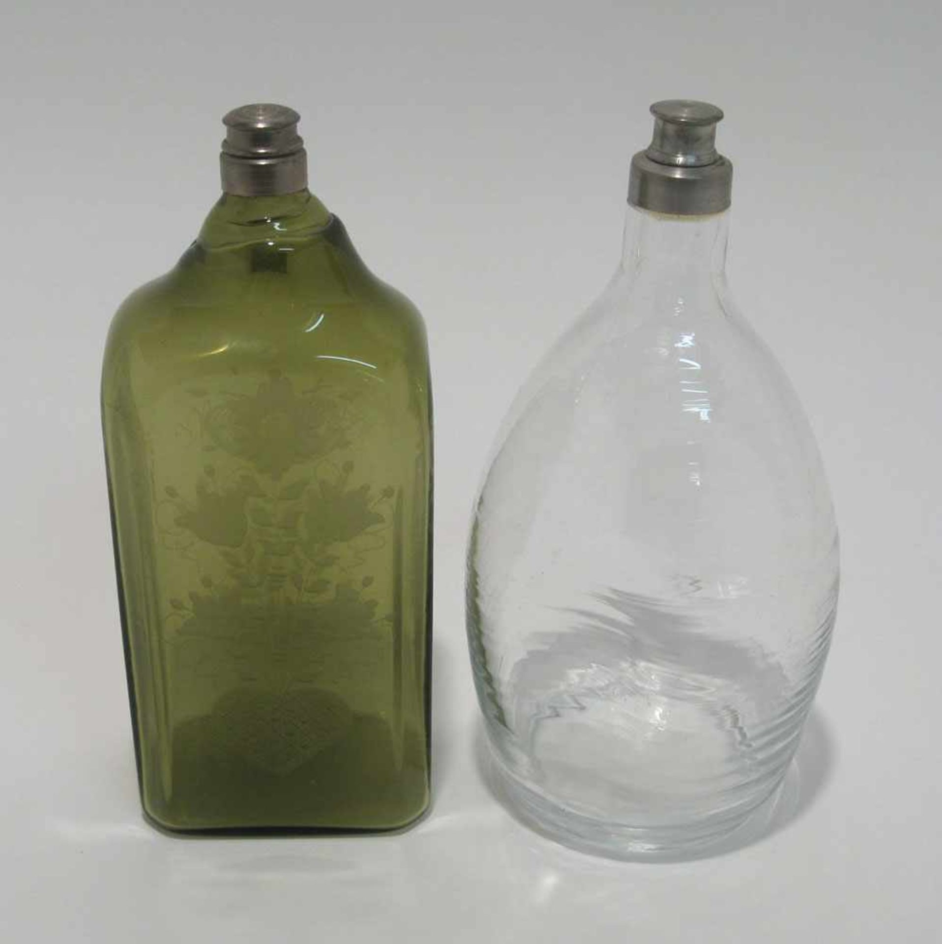 Zwei Flaschen Neuzeitlich. Grüne Vierkantflasche mit gerutschtem Dekor bzw. farblose ovale Flasche
