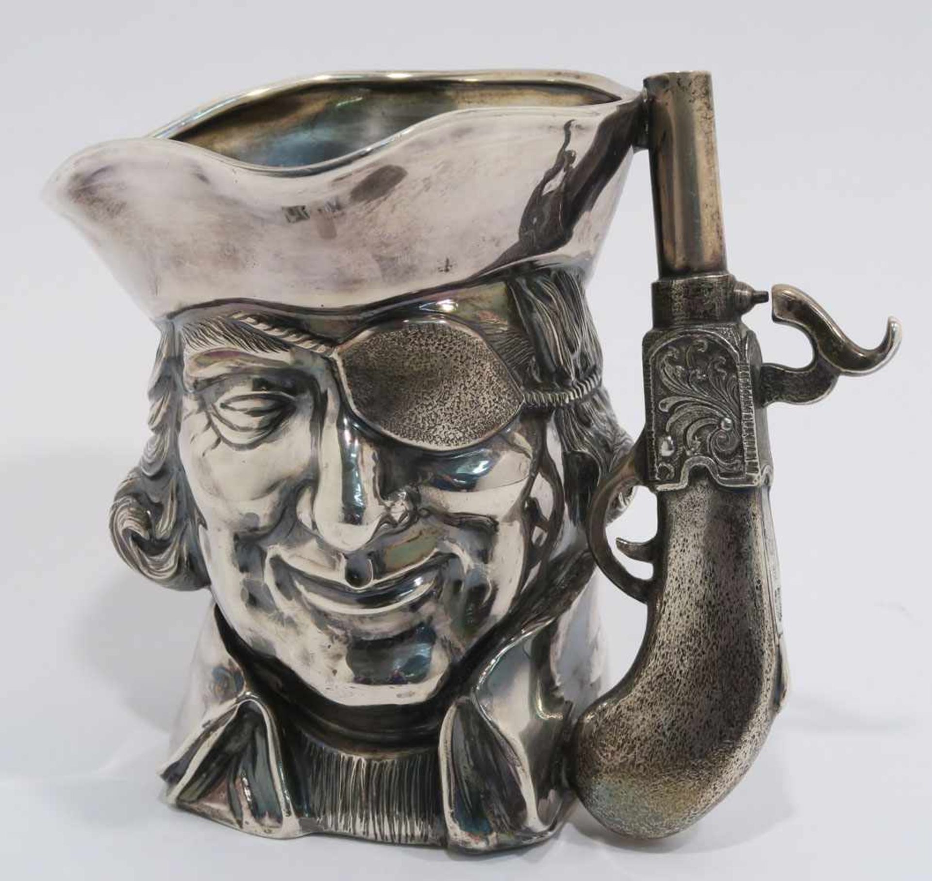 BecherIn Form eines Piratenkopfes mit Pistole als Griff. Italien (Neapel). Silber. Marken (800).